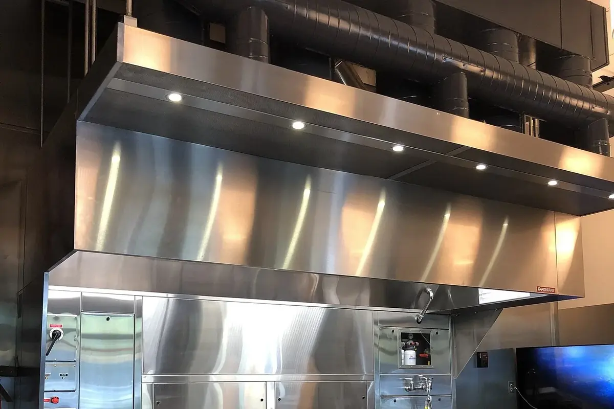 A stainless steel extraction hood over a commercial cooking line